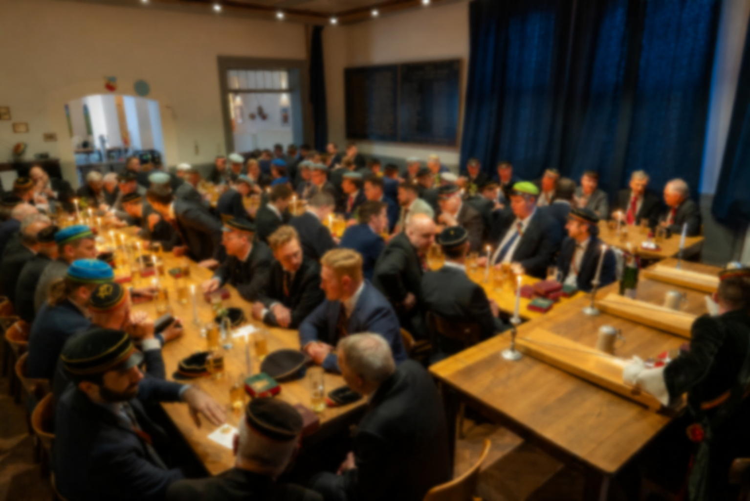 Teilnehmer eines Kommerses an langen, festlich gedeckten Tafeln